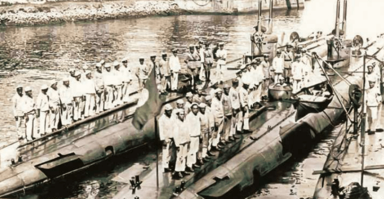 Foto em preto e branco com marinheiros da Marinha brasileira em cima dos três primeiros submarinos brasileiros, alinhados lado a lado no mar